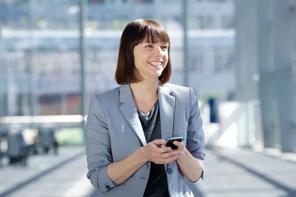 Smiling business woman walking with cell phone