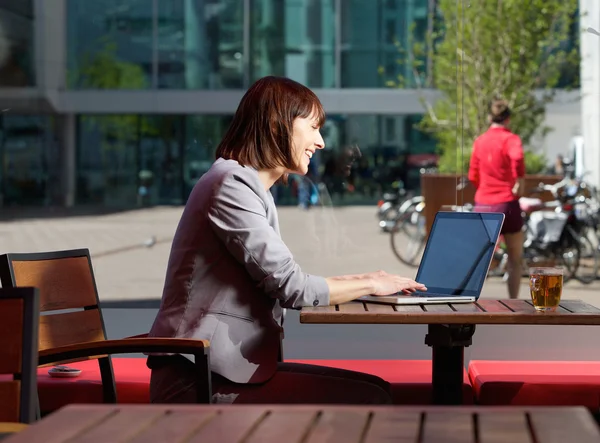 Glimlachende zakenvrouw met behulp van laptop in café — Stockfoto