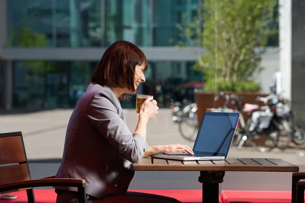 Zakenvrouw drinken thee en met behulp van laptop in café — Stockfoto