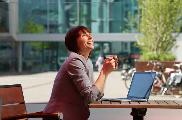 Affärskvinna skratta med kopp te och laptop — Stockfoto
