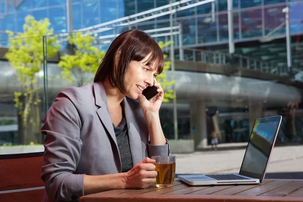 Business woman sitting at outdoor cafe with laptop — Stock Photo, Image