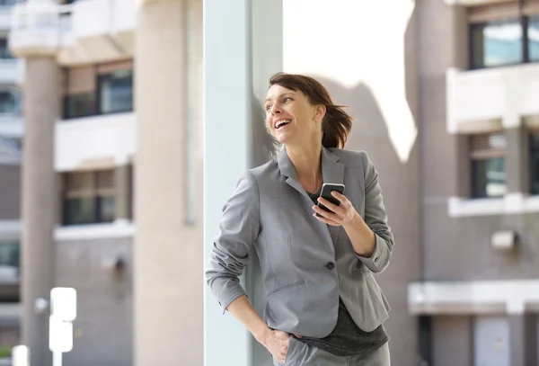 Affärskvinna som skrattar med mobiltelefon — Stockfoto