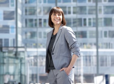 Smiling modern business woman standing in the city