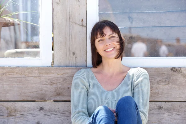 Счастливая женщина средних лет улыбается на открытом воздухе — стоковое фото