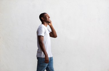 Yürüyüş ve cep telefonu üzerinde konuşurken gülümseyen adam