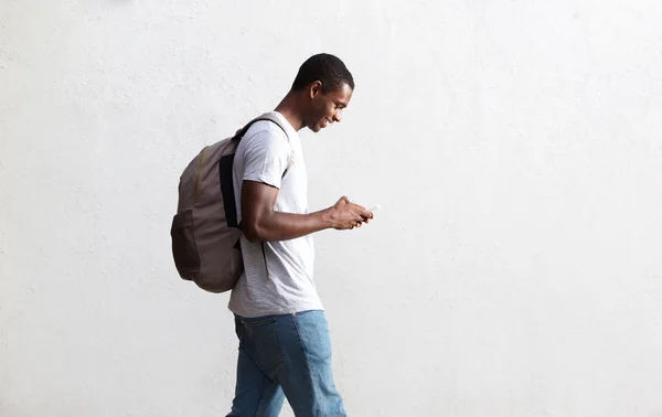 Estudante afro-americano caminhando com saco e telefone celular — Fotografia de Stock