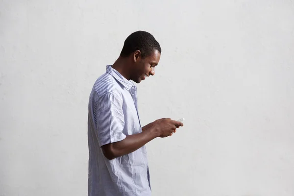 Smiling black guy walking and using mobile phone — Stock Photo, Image