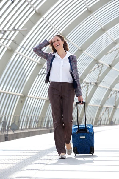Mulher de negócios sorrindo e andando na estação com saco — Fotografia de Stock