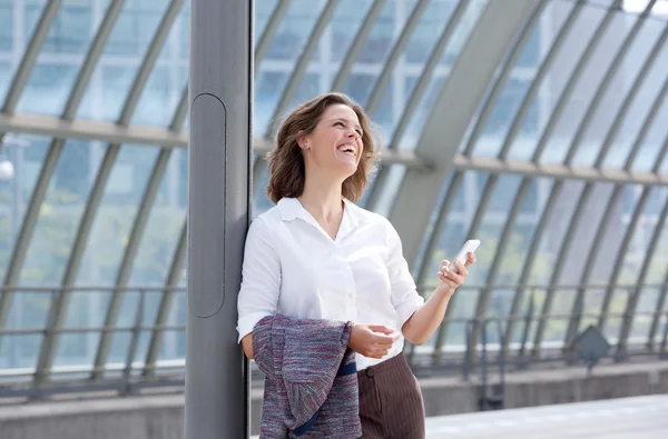 Leende affärskvinna med mobiltelefon tittar bort — Stockfoto