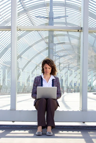 Business woman sitting outside using laptop