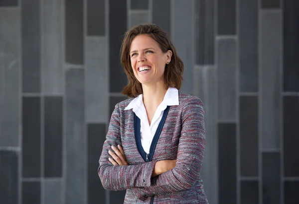 Mujer de negocios sonriendo con los brazos cruzados sobre fondo gris —  Fotos de Stock