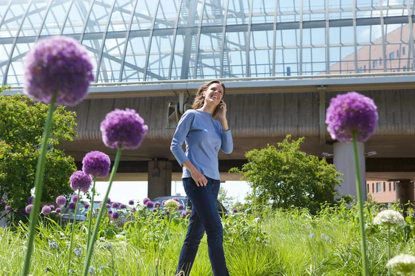 Woman walking alone in city park calling by cell phone — Stock Photo, Image