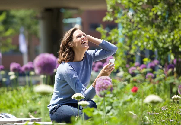 Mulher feliz tirando foto de flores no parque — Fotografia de Stock