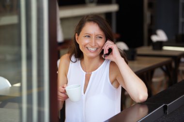 Kadın içme kahve gülümseyen ve istimal hareket eden telefon