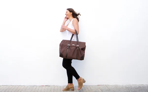 Щаслива жінка ходить з сумкою і мобільним телефоном — стокове фото