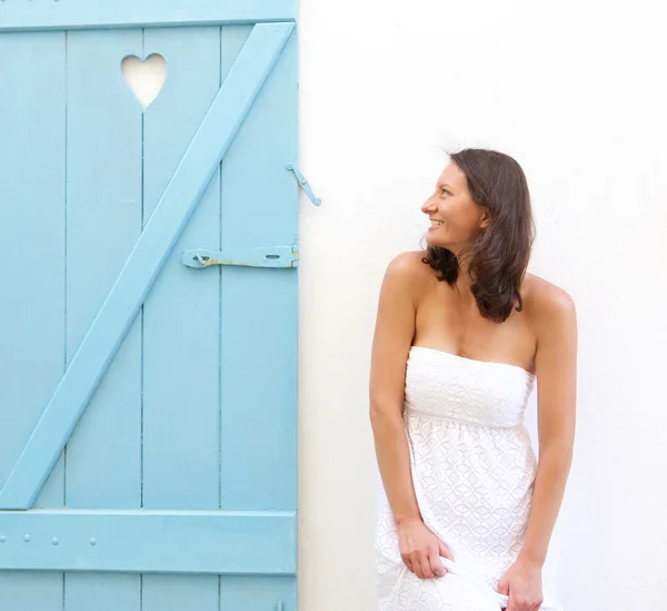 Smiling woman standing next to heart shape window shutter — Stock Photo, Image