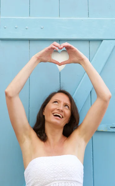 Mujer feliz haciendo forma de corazón con las manos —  Fotos de Stock