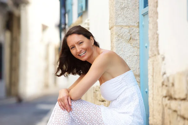 Happy woman sitting outside in summer dress — Stock Photo, Image