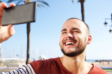 Cep telefonu ile bir selfie çekerken gülen genç adam 