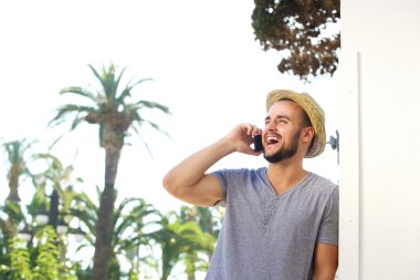 Cep telefonu için dinleme ve gülüyor şapka ile genç adam