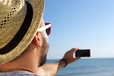 Genç adam bir selfie cep telefonu ile denizde alarak