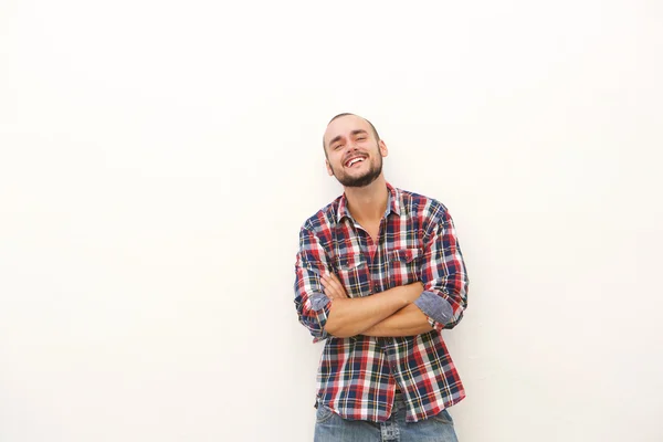 Улыбающийся молодой человек с бородой стоит напротив белой стены — стоковое фото