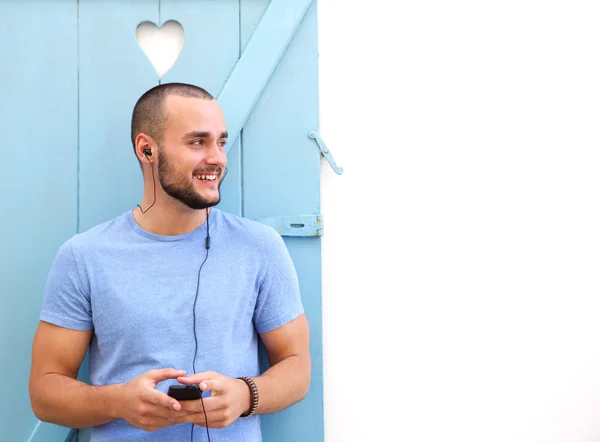 Glimlachende man luisteren naar muziek op mobiele telefoon met koptelefoon — Stockfoto
