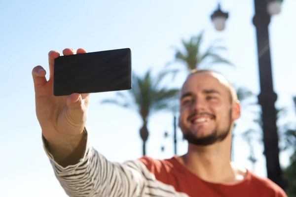 Sorridente giovane uomo prendendo un selfie con il suo telefono cellulare — Foto Stock