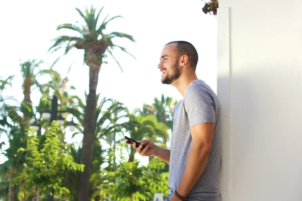 Sidan porträtt av en stilig ung man håller mobiltelefon — Stockfoto