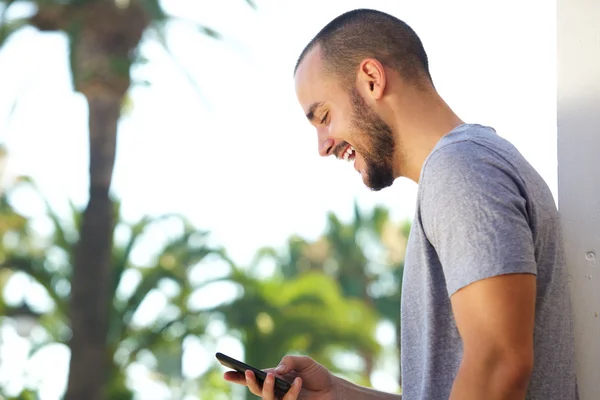 Fröhlicher junger Mann liest SMS auf Handy — Stockfoto