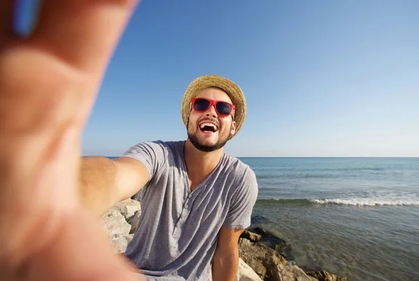 Muž na dovolené, směje se na pláži s selfie — Stock fotografie