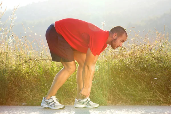 Hombre deportivo ajustando su zapato antes de correr ejercicio —  Fotos de Stock