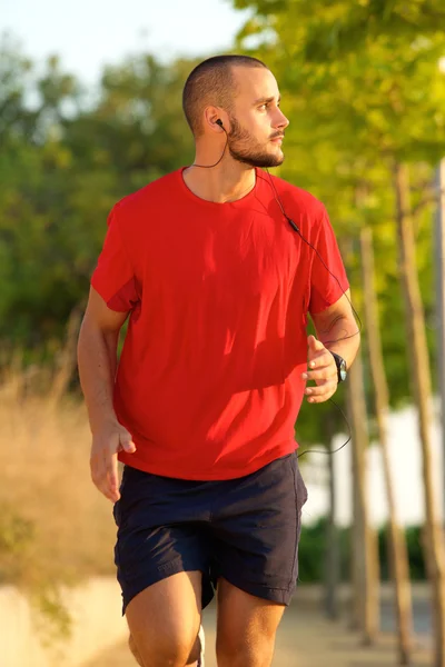 Young man running with earphones outside — Stock Photo, Image