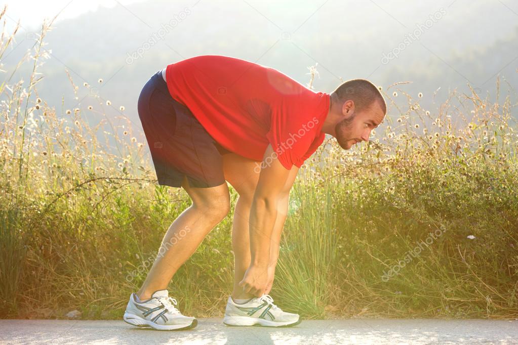 Sports man adjusting his shoe before running exercise