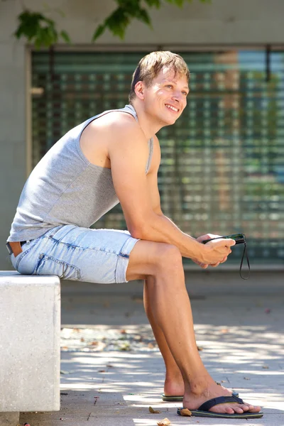 휴대 전화를 밖으로 앉아 행복 한 젊은 사람 — 스톡 사진