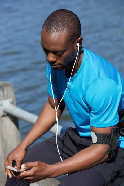 Sportovní muž sedí mimo poslech hudby v mobilním telefonu — Stock fotografie