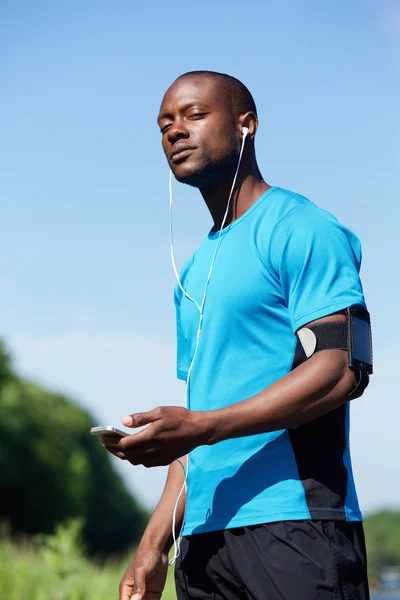 Hombre deportivo parado afuera con teléfono y auriculares —  Fotos de Stock