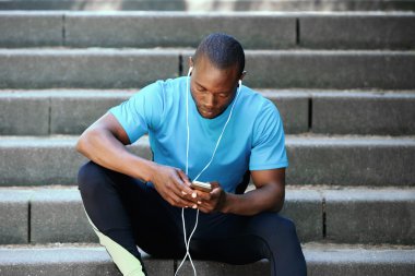 Cep telefonu ile müzik dinlemek adımlar üzerinde oturan