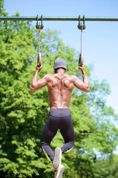 Un homme afro-américain fort se tenant sur des anneaux de gymnaste — Photo