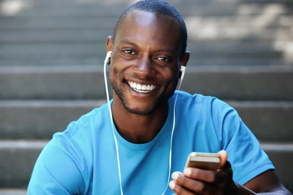 Killen som innehar mobiltelefon lyssna på musik i hörlurar — Stockfoto
