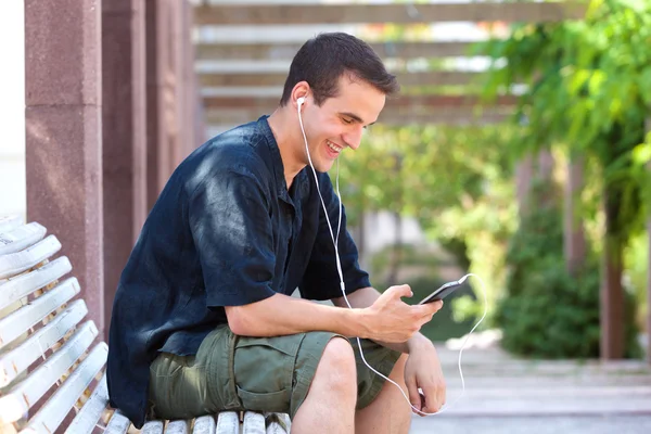 Homem sorridente ouvindo música no celular — Fotografia de Stock