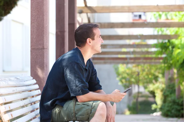 Usmívající se muž drží mobilní telefon a koukal — Stock fotografie