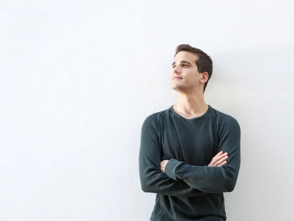 Young man standing against white background with arms folded — Stock Photo, Image