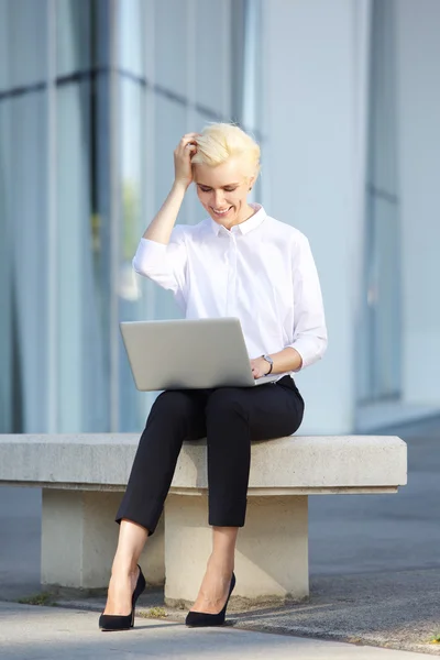 Vrolijke jonge zakenvrouw met behulp van laptop buiten — Stockfoto