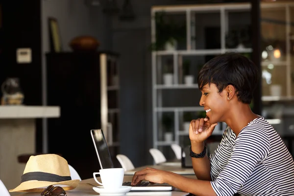Sorrindo jovem afro-americana trabalhando no laptop — Fotografia de Stock