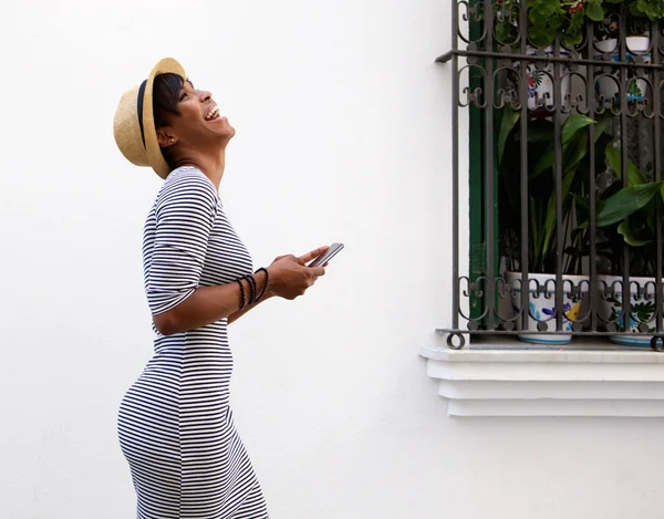 Ridendo giovane donna che cammina con il telefono cellulare — Foto Stock