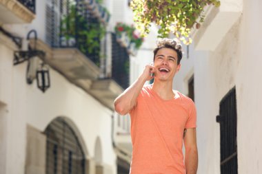 Cep telefonu ile şehirde yürüyüş gülümseyen genç adam