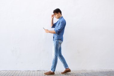 Yürüyüş ve cep telefonu kısa mesaj okuma genç adam