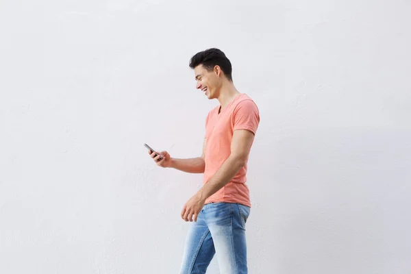 Lachende jonge man lopen en kijken naar mobiele telefoon — Stockfoto