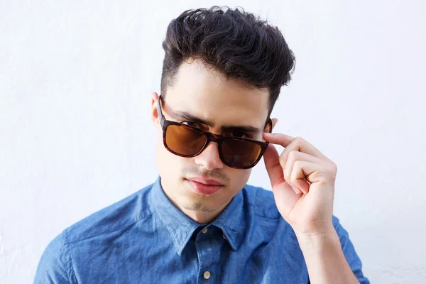 Cool young guy peeking over sunglasses — Stock Photo, Image